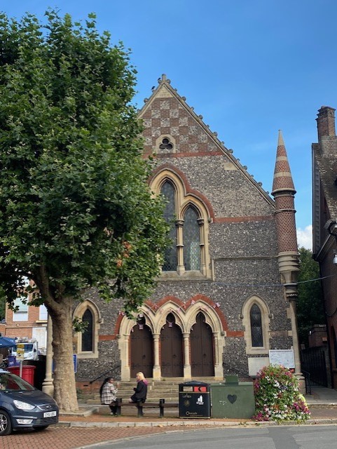 The United Reformed Church, an imposing, gothic style flint and brick building with steps down to The Broadway.